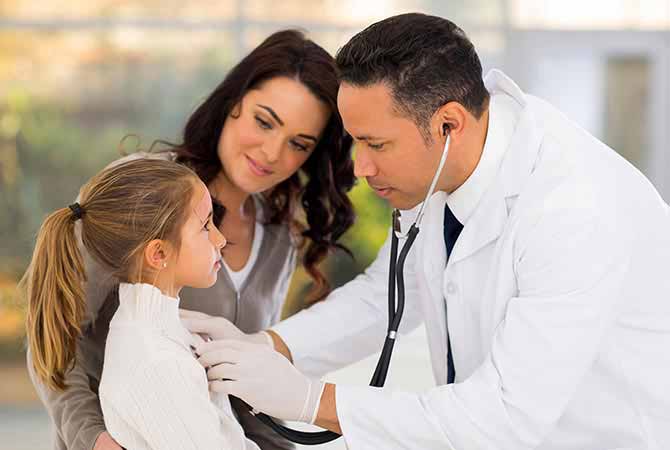 Doctor listening young girls heart beat with mother watching