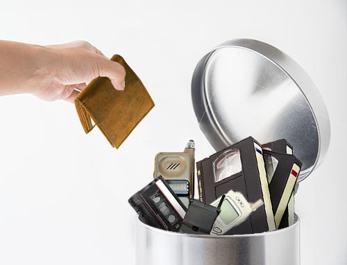 Wallet and old technology in trashcan